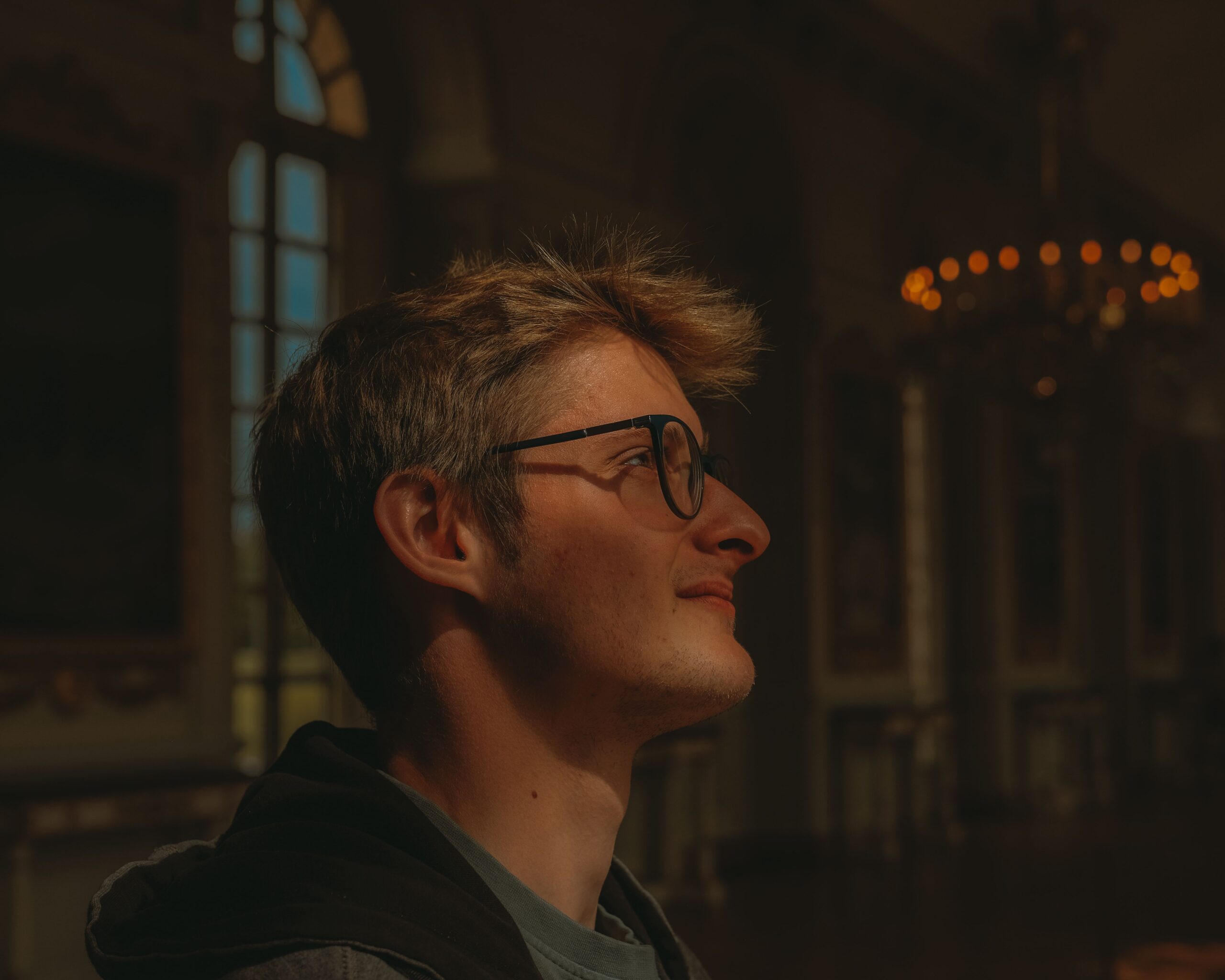 Side profile of a man in a historic Versailles hallway, gazing upwards.