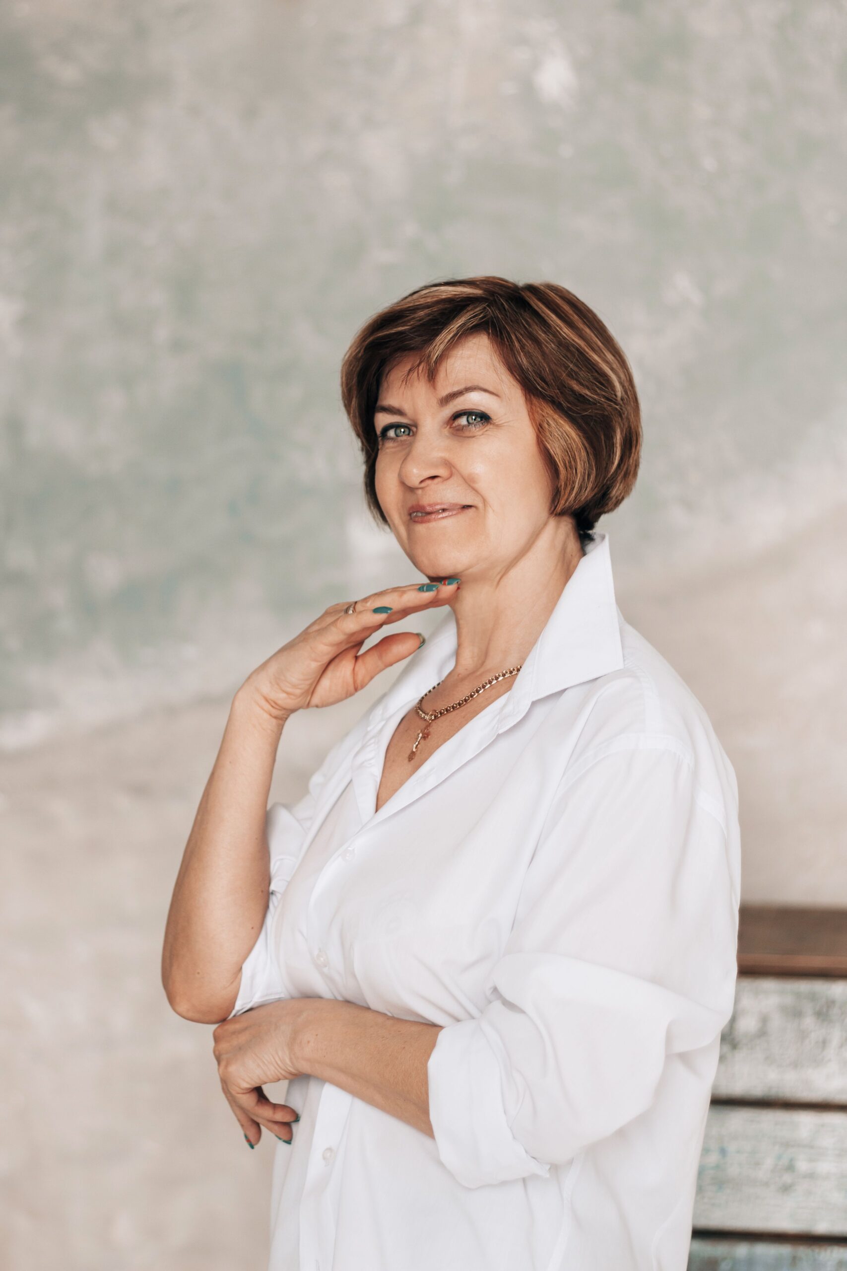 Portrait of a senior woman posing confidently in a white blouse, showcasing elegance and style.
